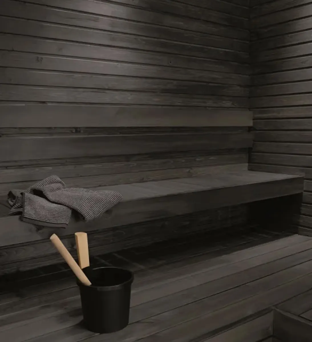 Black sauna interior with towel and wooden bucket