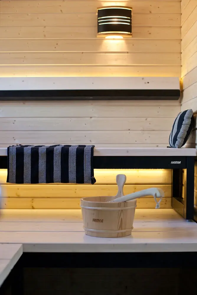 Sauna bench with backlighting, a wall lamp and a wooden bucket